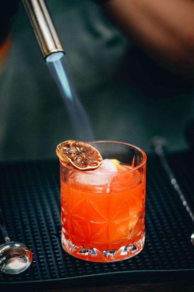 Vibrant cocktail with citrus garnish being torched for a unique flavor.